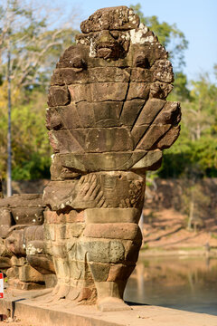 Close view of a weathered stone naga balustrade at the bridge entrance to Angkor Thom near Siem Reap, Cambodia. The multi-headed serpent sculpture displays intricate carvings and textured surfaces