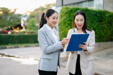 Fototapeta premium Businesswoman and woman going in city center in smart casual business style, talking, working together, stylish freelance people, holding coffee