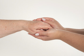 Fototapeta premium Woman holding grandmothers hand. Care and help concept. Young hand holding an old hands. Elderly woman hands close up. Hand help bridges age. Hand help connects old young.