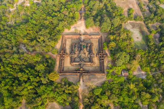 Aerial perspective reveals the symmetrical layout of Banteay Samre temple surrounded by dense tropical forest in the Angkor region of Cambodia. The ancient sandstone structure stands out amid rural