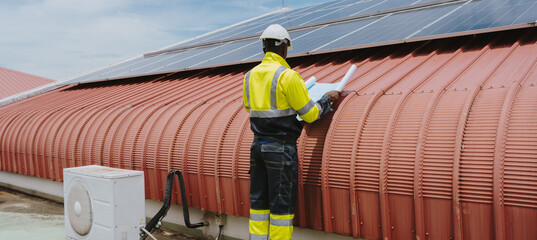 Engineers are checking the hot coil system of the rooftop air conditioner for green energy. Solar panels on the roof of the factory.(PHOTO)	