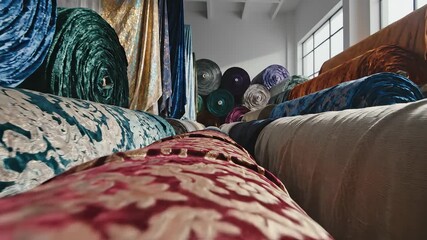 A vibrant array of intricately patterned fabric rolls showcasing a rich tapestry of colors and textures meticulously stacked in a textile warehouse or design studio ready for fashion upholstery and i.