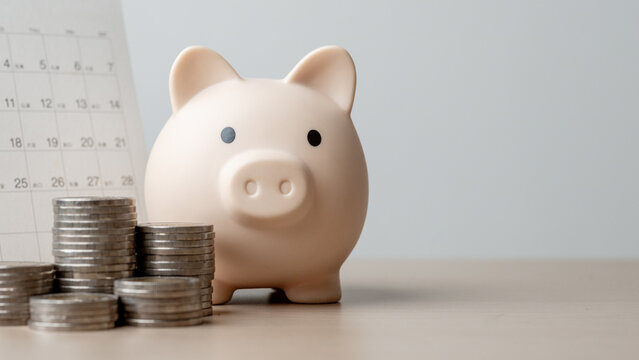Piggy bank with stacked coins and calendar background representing bill reminder, recurring payment schedule, monthly budgeting, expense tracking, and personal financial planning concept.
