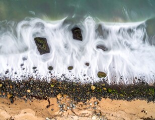 Aerial view of a foamy ocean meeting a rocky shore