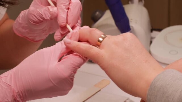 Fingernails artist salon. Professional manicure procedure. Manicurist woman hands making hardware machine to beauty nail client using wooden stick to push back cuticle.