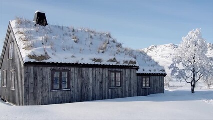 Rustic wooden house with grass roof nestled in a snowy landscape with a snow-covered tree