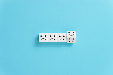 Flipping of dice from sad to smile emotion on blue background.
