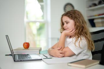Kid preparing for exam with laptop. Student sitting at desk during distance education class. Smart child in virtual schoolwork and study. Child learning mathematics on laptop in home classroom.