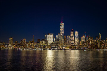 Obraz premium Manhattan night skyline. New York City wide panoramic skyline. New York cityscape along the waterfront. NYC aerial skyline above downtown Manhattan. New York City landscape with skyscrapers.