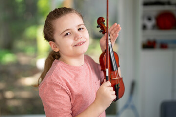 Child artist enjoying violin practice. Young musician learning music on violin. Girl practicing acoustic violin indoors. Kid enjoying hobby and playing violin. Child practicing classic musical