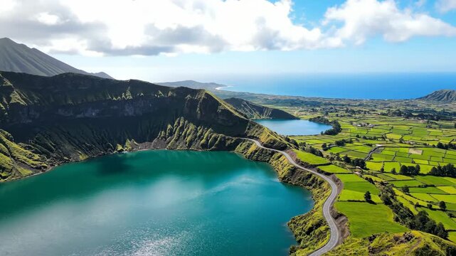 Breathtaking Aerial View of Sete Cidades Lake in Azores Portugal Featuring Volcanic Crater Lake Turquoise Waters Lush Green Hills and Winding Road Under Bright Blue Sky With White Clouds