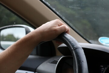 Hand on steering wheel of person driving car