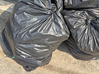 Close-up of tied black garbage bags on a concrete surface, symbolizing waste management, sanitation, and urban cleaning services.