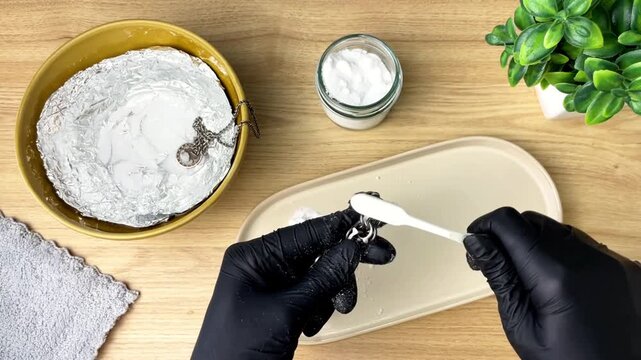 The process of cleaning tarnish from silver jewelry using baking soda and a toothbrush at home.