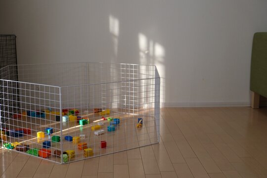 Colorful plastic toy blocks scattered on the floor inside a baby playpen.