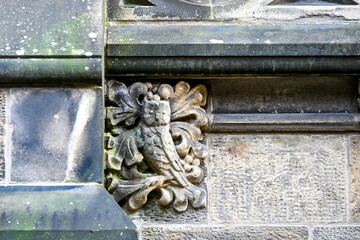 Stone owl carving detail set into a historic Glasgow building facade, weathered by time.