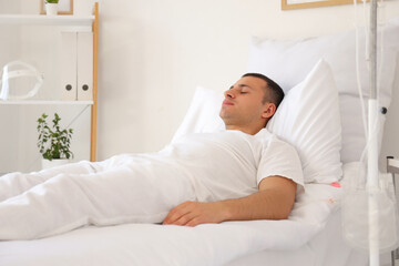 Male patient sleeping on bed in hospital ward
