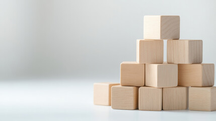 Obraz premium Wooden block pyramid stack on white surface with soft natural light creating calm and minimalistic atmosphere