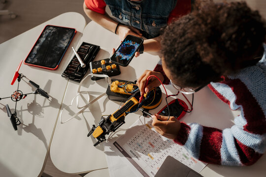 High school students working on robotics project, using online AI app to answer questions.