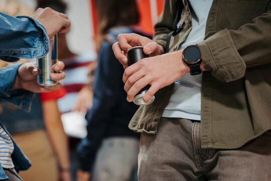 Teen students drinking an energy drink in school hallway.