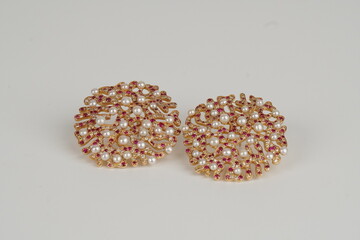 Elegant filigree-style gold earrings featuring intricate metalwork adorned with luminous pearls and vibrant ruby gemstones. This luxurious jewelry design combines traditional craftsmanship with timele