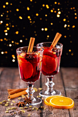 Mulled wine. Festive beverage featuring rich red liquid, garnished with orange slices and spices, served in elegant glasses on wooden table, creating warm and inviting atmosphere for celebrations