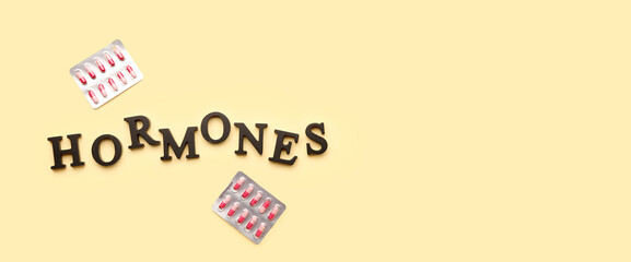 Obraz premium Word HORMONES with pills on yellow background