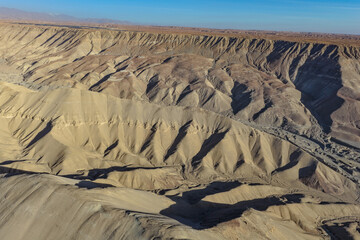 Aerial view of arid desert mountains and cliffs at dawn