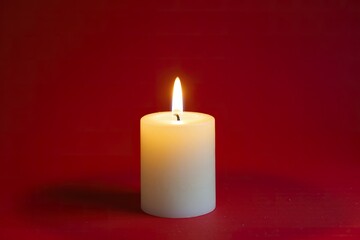 Single candle with soft flame, red background, warm golden light, minimalist festive atmosphere, elegant Lunar New Year