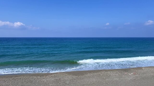 The Mediterranean Sea and the foaming waves in Mahmutlar during the day in sunny weather. Alanya. The waves crash against the shore. The turquoise water on the beach in Turkey.The coastline is wide.4К