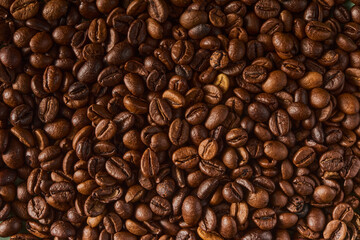 Fototapeta premium Roasted coffee beans texture background. Full frame closeup of aromatic arabica grains. Top view pattern of brown caffeine ingredient. Fresh energy drink wallpaper