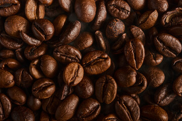 Naklejka premium Roasted coffee beans texture background. Full frame closeup of aromatic arabica grains. Top view pattern of brown caffeine ingredient. Fresh energy drink wallpaper