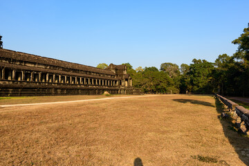 Long sandstone colonnade of the honor terrace at Angkor Vat stretches beside a wide expanse of dry...
