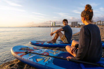 Fototapeta premium Friends share a joyful moment at the beach during sunset, holding vibrant surfboards while laughing