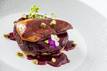 Indulge in seared foie gras atop sweet fruit sauce, garnished with pistachios © Maksim Shebeko