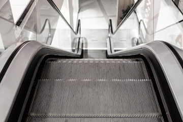 Close-up view of an empty escalator going down, captured from the top step with a focus on the...