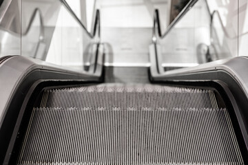 Close-up view of an empty escalator going down, captured from the top step with a focus on the...