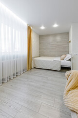 Modern studio apartment interior with bed and large window