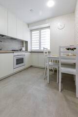 Bright modern kitchen and dining area with white furniture