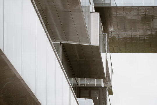 Abstract modern corporate architecture building facade of glass windows beneath a sleek canopy showing engineered geometry pattern and deep shadow