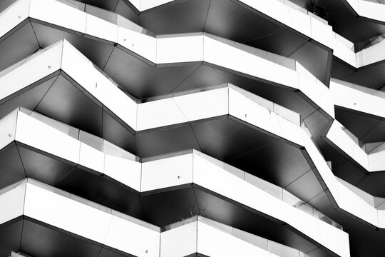 Abstract modern corporate architecture building facade of glass windows with zigzag terraces and strong geometry pattern in monochrome light