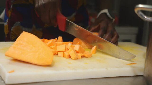 Close up of an African chef cutting yam and sweet potato into concass&eacute; pieces, using Dioscorea rotundata known as yam, igname, &ntilde;ame, inhame and Ipomoea batatas called sweet potato, batata, slow motion