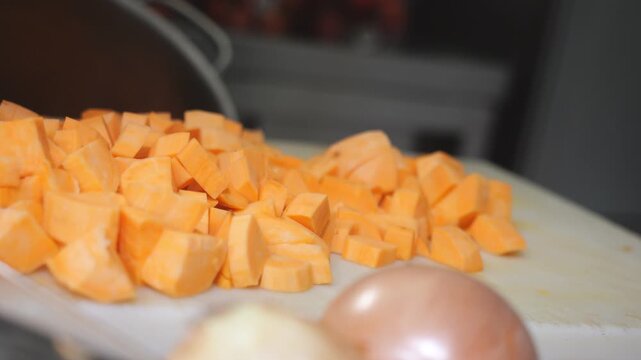 Close up of an African chef cutting yam and sweet potato into concass&eacute; pieces, using Dioscorea rotundata known as yam, igname, &ntilde;ame, inhame and Ipomoea batatas called sweet potato, batata, slow motion