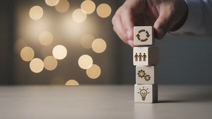 Stacked wooden blocks with icons &mdash; hand stacking concept for planning, teamwork, and growth

