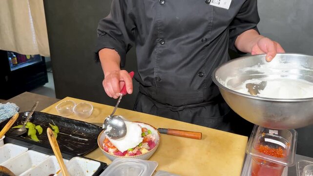 Chef in Black Uniform Scooping White Foam onto Raw Tuna Bowl