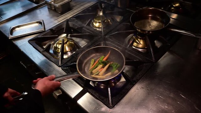 Professional chef flambeing and tossing fresh vegetables in a pan