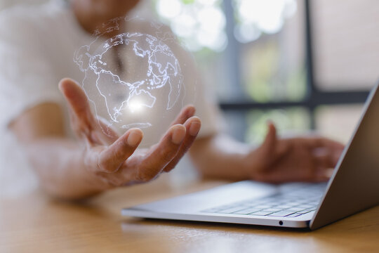 Senior person holding glowing digital globe hologram above hand with laptop. Concept of global connectivity, data network, future technology, digital transformation, innovation worldwide business comm - Powered by Adobe