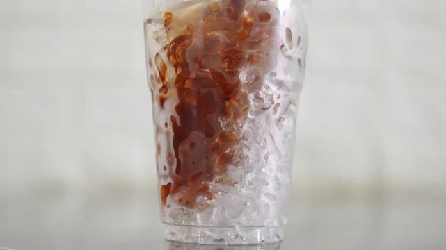 4K Iced coffee with ice cubes in a clear plastic cup on wooden table Refreshing cold beverage, Concept showing simplicity freshness takeaway drink cafe lifestyle.