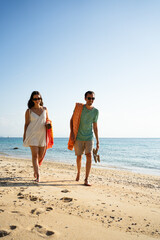 Couple walking barefoot on a sandy beach by the ocean