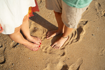 Couple's bare feet standing on beach sand